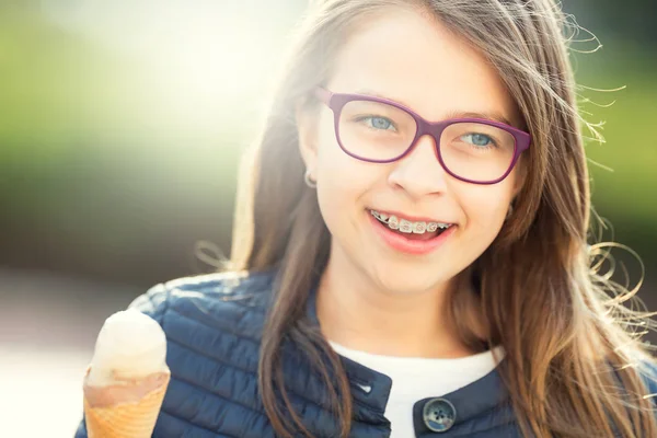 Girl. Teen. Pre teen. Girl with ice cream. Girl with glasses. Girl with teeth braces. Young cute caucasian blond girl wearing teeth braces and glasses. Portrait of a smiling young girl — Stock Photo, Image