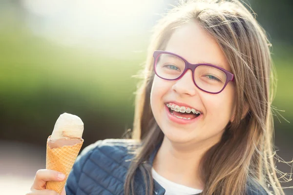 Girl. Teen. Pre teen. Girl with ice cream. Girl with glasses. Girl with teeth braces. Young cute caucasian blond girl wearing teeth braces and glasses. Portrait of a smiling young girl — Stock Photo, Image
