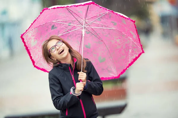 Portrait of happy beautiful young pre-teen girl with pink umbrella under rain — Stock Photo, Image