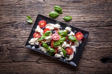 Caprese Salad.Mediterranean salata. Mozzarella peyniri domates fesleğen ve zeytinyağı eski meşe masada. İtalyan mutfağı