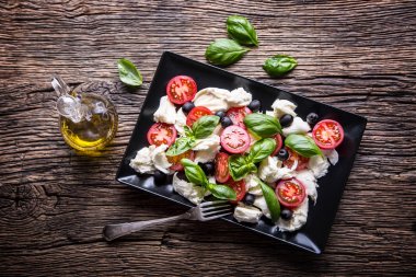 Caprese Salad.Mediterranean salata. Mozzarella peyniri domates fesleğen ve zeytinyağı eski meşe masada. İtalyan mutfağı