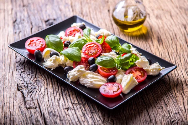 Salade Caprese.Salade méditerranéenne. Mozzarella tomates cerises basilic et huile d'olive sur une vieille table en chêne. Cuisine italienne — Photo