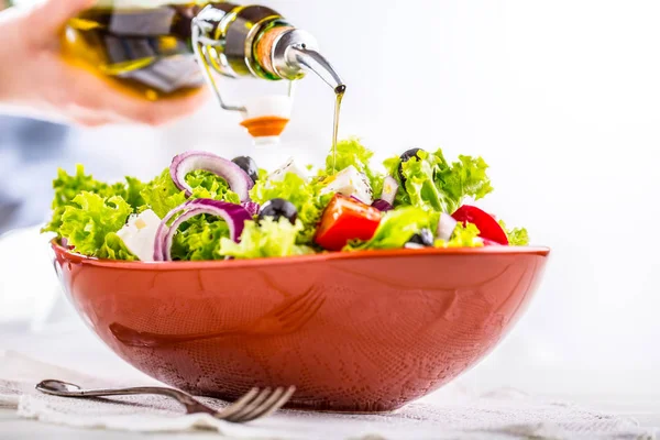 Salat. Vegetabilsk salat. Vårsalat av grønnsaker. Frisk vegetabilsk salat med tomater, løkost og olives.Olivenolje som øses i salatbollen – stockfoto