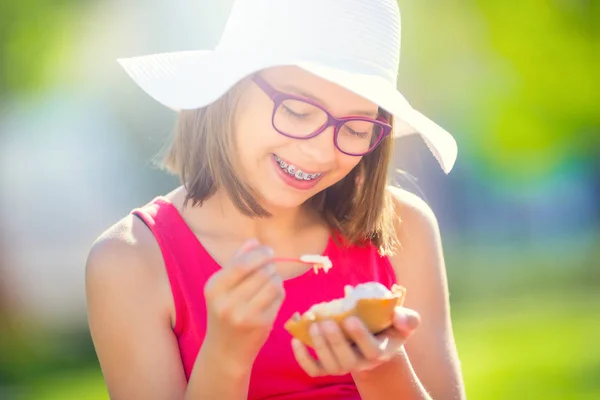 Cheerful teenage girl with dental braces glasses and ice cream. Portrait of a smiling pretty young girl in summer outfit with ice cream and teeth braces — Stock Photo, Image