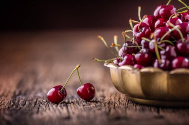 Kiraz. Taze tatlı kiraz. Eski meşe masada retro kase damla su ile lezzetli kiraz