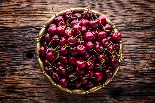 Cherries. Fresh sweet cherries. Delicious cherries with water drops in retro bowl on old oak table