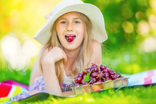 Niño con cerezas. Niña con cerezas frescas. Retrato de una joven sonriente con un tazón lleno de cerezas frescas — Foto de Stock