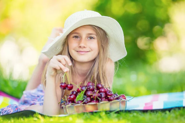 Niño con cerezas. Niña con cerezas frescas. Retrato de una joven sonriente con un tazón lleno de cerezas frescas — Foto de Stock