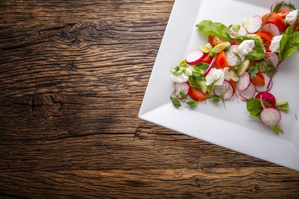 蔬菜沙拉。板的质朴的橡木桌子上的蔬菜沙拉。各式各样的蔬菜沙拉配料 — 图库照片