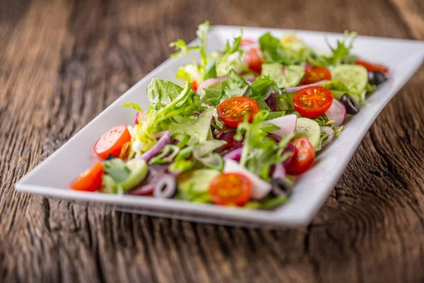 Grönsakssallad. Tallrik med sallad med grönsaker på rustika ekbordet. Sortiment av ingredienser av grönsakssallad — Stockfoto