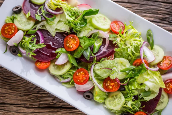 Grönsakssallad. Tallrik med sallad med grönsaker på rustika ekbordet. Sortiment av ingredienser av grönsakssallad — Stockfoto
