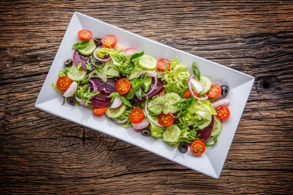 蔬菜沙拉。板的质朴的橡木桌子上的蔬菜沙拉。各式各样的蔬菜沙拉配料 — 图库照片