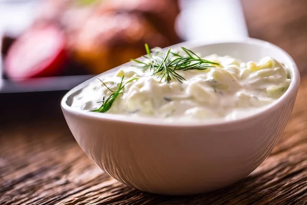 Tzatziki. Tzatziki saus dip of dressing met kip grill benen in de achtergrond — Stockfoto