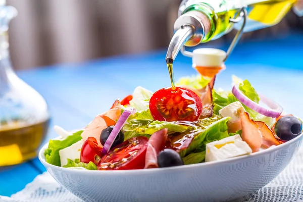 Salat. frischer Sommersalat. Gesunder mediterraner Salat Oliven Tomaten Parmesan-Käse und Schinken. Gießen von Olivenöl — Stockfoto