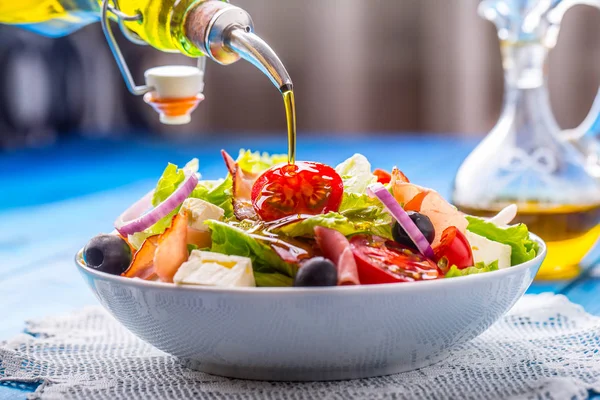 Sałatka. Letnia Sałatka sałata. Zdrowe sałatki śródziemnomorskiej oliwki pomidory ser parmezan i prosciutto. Wlewanie oleju z oliwek — Zdjęcie stockowe