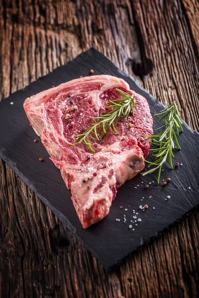 Carne de res carne cruda. Filete crudo de hueso en T fresco con sal, pimienta y rosa — Foto de Stock
