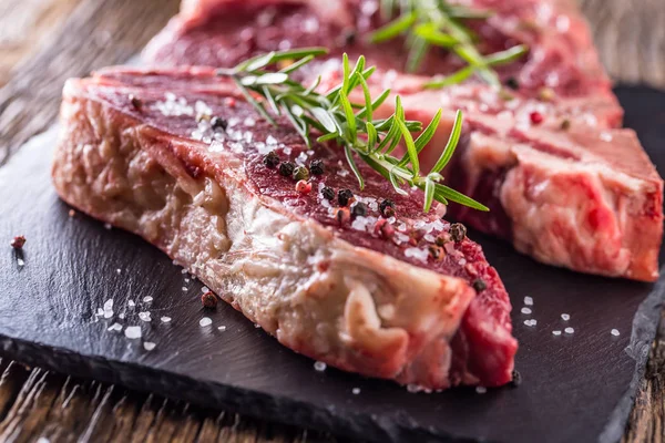 Carne de res carne cruda. Filete crudo de hueso en T fresco con sal, pimienta y rosa — Foto de Stock