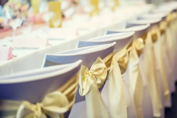 Casamento. Cadeiras de casamento em linha decoradas com fita de cor amarela dourada — Fotografia de Stock