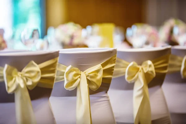 Casamento. Cadeiras de casamento em linha decoradas com fita de cor amarela dourada — Fotografia de Stock