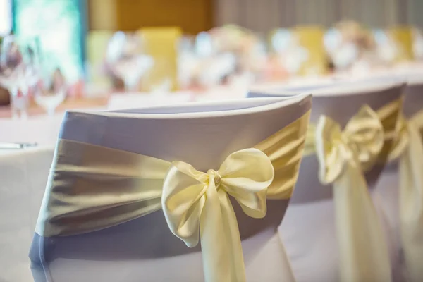 Свадьба. Свадебные стулья в ряд украшены золотисто-желтой лентой цвета — стоковое фото