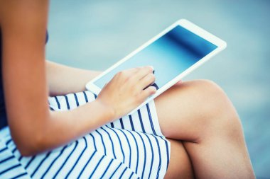 Elinde bir tablet ile oturan genç çekici kız