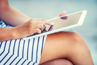 Elinde bir tablet ile oturan genç çekici kız