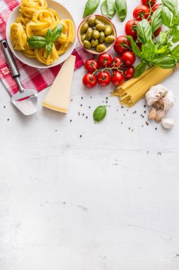 İtalyan yemeği mutfağı ve malzemelerin üzerine beyaz beton tablo. Spagetti Tagliatelle zeytin zeytinyağı domates parmesan peynir sarımsak biber ve fesleğen yaprakları ve Damalı masa örtüsü. Metin veya bilgi için boş alan