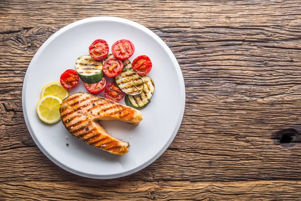 Du saumon. Steak de saumon grillé aux tomates et courgettes sur assiette blanche — Photo