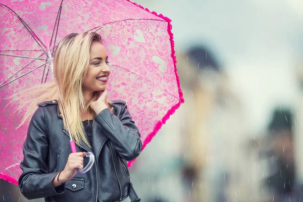 Приваблива молода жінка з рожевою парасолькою під дощем і сильним вітром. Дівчина з парасолькою в осінню погоду . — стокове фото