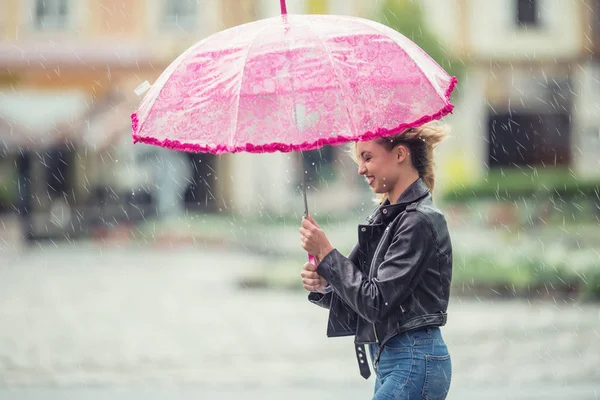 Attraente giovane donna con ombrello rosa sotto la pioggia e forte vento. Ragazza con ombrello in autunno . — Foto Stock