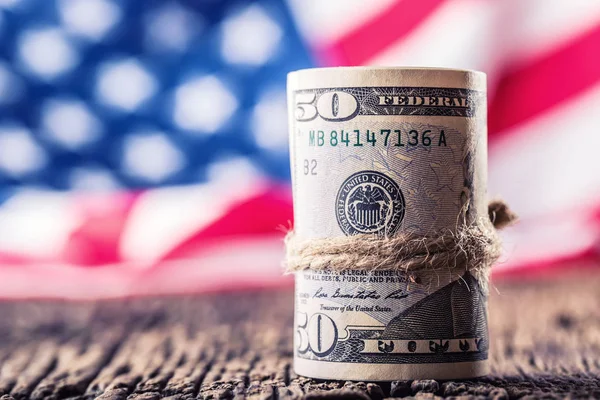 Billetes rodados en dólares primer plano con bandera americana en el fondo. Dinero en efectivo Dólares Americanos.Vista de primer plano de la pila de dólares estadounidenses — Foto de Stock