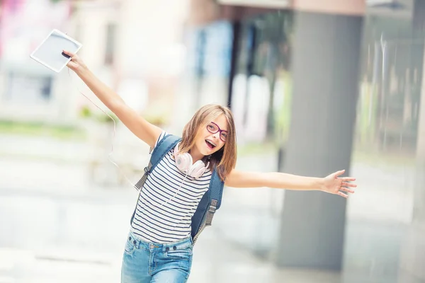 Colegiala con bolsa, mochila. Retrato de niña adolescente feliz moderna con audífonos de mochila bolsa y tableta. Chica con aparatos dentales y gafas — Foto de Stock