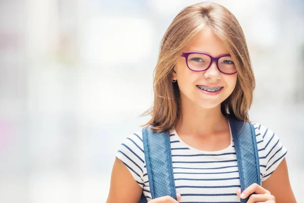 Studentessa con borsa, zaino. Ritratto di moderna adolescente felice ragazza della scuola con zaino borsa. Ragazza con apparecchio dentale e occhiali — Foto Stock