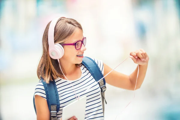 Uczennica z torba, plecak. Portret nowoczesne szczęśliwy Nastolatki uczennice z torba plecak słuchawki i tabletu. Dziewczyna z aparatów na zęby i okulary — Zdjęcie stockowe