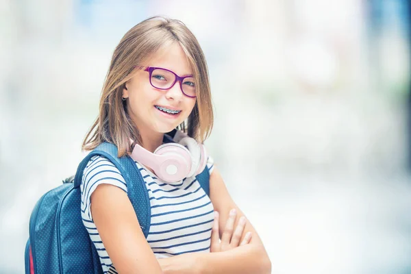 Estudante com saco, mochila. Retrato da menina da escola adolescente feliz moderna com fones de ouvido mochila saco e tablet. Menina com aparelho dental e óculos — Fotografia de Stock