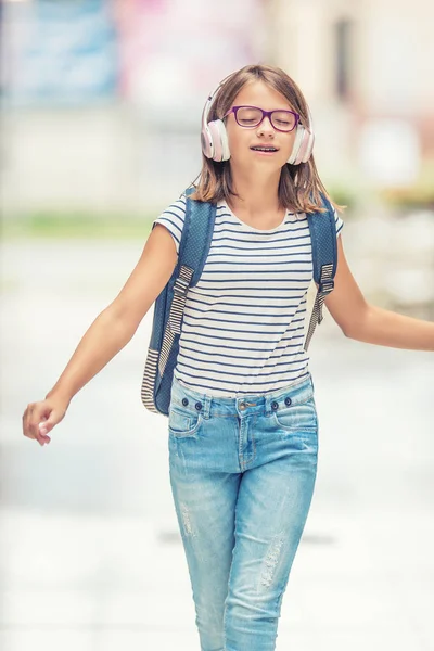 Estudante com saco, mochila. Retrato da menina da escola adolescente feliz moderna com fones de ouvido mochila saco e tablet. Menina com aparelho dental e óculos — Fotografia de Stock