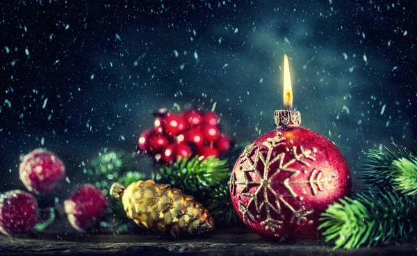 Vánoční svíčka. Vánoční hořící svíčka s vánoční ozdoby v zasněžené atmosféře — Stock fotografie