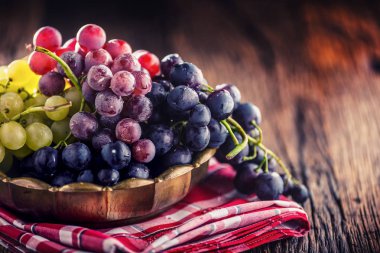 Üzüm. Eski meşe masada retro kase çok renkli üzüm demet