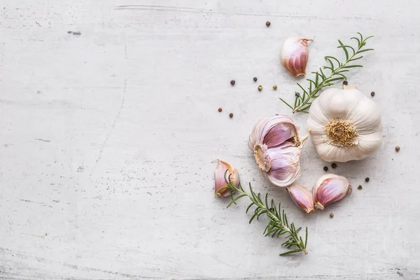 Garlic. Garlic bulbs. Fresh garlic with rosemary and pepper on white concrete board