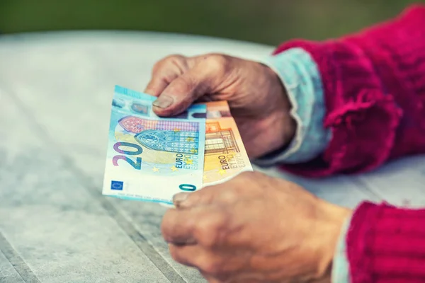 Pensionista sosteniendo en sus manos billetes en euros —  Fotos de Stock