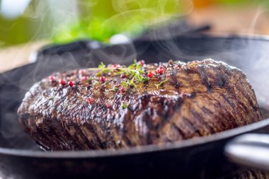 Sığır eti biftek. Ot ve biber ile ahşap tahta üzerinde tavada sulu kaburga eti