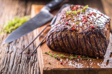 Sığır eti biftek. Ot ve biber ile ahşap tahta üzerinde tavada sulu kaburga eti