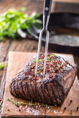 Sığır eti biftek. Çatal ile ahşap tahta üzerinde tavada sulu kaburga eti