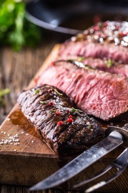 Sığır eti biftek. Sulu orta kaburga biftek dilimleri ahşap tahta çatal ve bıçak otlar baharatlar ve tuz ile