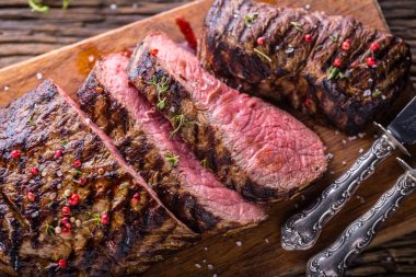 Sığır eti biftek. Sulu orta kaburga biftek dilimleri ahşap tahta çatal ve bıçak otlar baharatlar ve tuz ile