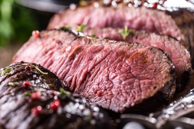 Sığır eti biftek. Sulu orta kaburga biftek dilimleri ahşap tahta çatal ve bıçak otlar baharatlar ve tuz ile