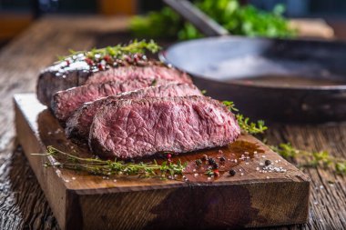 Sığır eti biftek. Sulu orta kaburga biftek dilimleri ahşap tahta çatal ve bıçak otlar baharatlar ve tuz ile