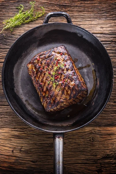 Sığır eti biftek. Ot ve biber ile ahşap tahta üzerinde tavada sulu kaburga eti