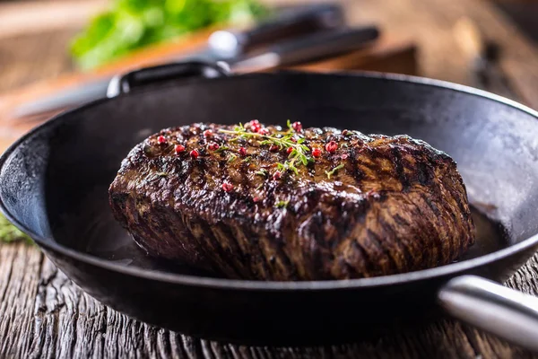 Nötstek. Saftig entrecôte stek i stekpanna på träskiva med ört och peppar — Stockfoto