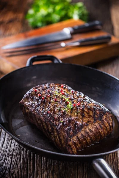 Carne de res. Juicy Rib Eye filete en sartén sobre tabla de madera con hierba y pimienta — Foto de Stock